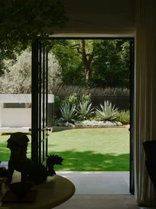 A well-maintained outdoor living area with a green lawn, potted plants, and a patio