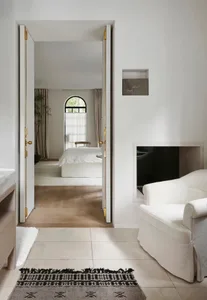 Open living area with a bed in the bedroom and a sofa in the living room, surrounded by natural light and greenery