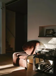 A modern living area with a brown leather chair in front of a white wall, accompanied by decorative bottles, conveying a sense of comfort and sophistication