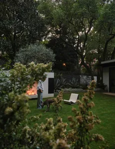 A relaxed outdoor living area with a fire pit, two chairs, and a bench, set amidst a natural landscape