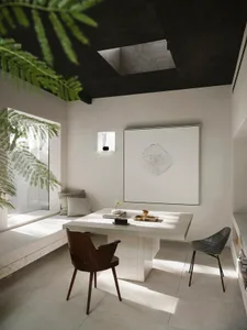 A well-lit living area with a white table surrounded by chairs, creating a cozy seating arrangement, with natural sunlight coming through windows
