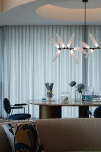 Dining area with a round table, chairs, a vase, and a teddy bear, set in a sophisticated and playful atmosphere