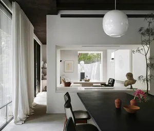 Open living area with white walls, a dining table, chairs, potted plants, and decorative vases and bowls, set in a well-lit and inviting space with a modern design style