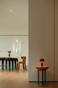 A modern dining space with a glass table, surrounded by chairs and decorated with vases, creating a cozy and inviting atmosphere