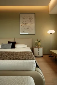 A cozy bedroom with a wooden floor, a large bed with white sheets and a brown blanket, and a vase with flowers adding a touch of elegance