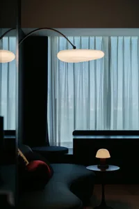 Cozy modern living area with a couch near a window, lamps on either side, and drawn curtains