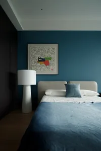 Cozy bedroom with a wooden floor, a large bed with a white comforter, and a lamp providing soft illumination