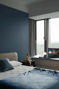 Cozy bedroom with two beds, a chair, and books, featuring a large window with natural light and a white color scheme
