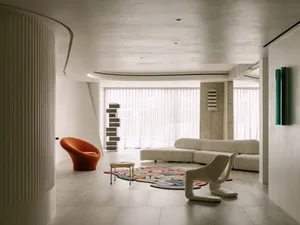 A modern living area with a white couch, two chairs, and decorative vases, featuring a clean, bright, and inviting atmosphere