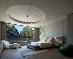 A large bedroom with a bed, two nightstands, and two chairs, surrounded by white walls and a modern design
