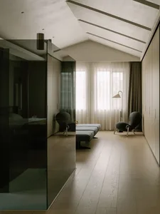 Empty living room with wooden floors and white walls, featuring a couch and two chairs