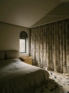 Cozy bedroom with a white comforter, oriental curtains, and dim lighting