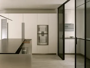 A modern kitchen with white cabinets, two ovens, a refrigerator, and a clean and organized atmosphere