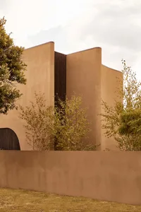 A modern house with a stucco exterior, surrounded by trees, creating a warm and inviting atmosphere