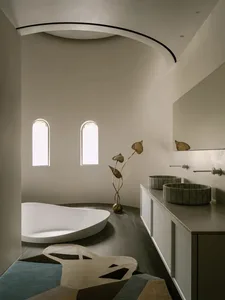 Modern bathroom with a large bathtub, two sinks, white walls, and wooden flooring, featuring a clean and bright atmosphere