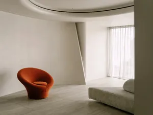 Modern living room with a minimalist aesthetic, featuring a large couch, two chairs, and a dining table, with a focus on functionality and openness