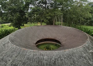 A serene interior space with a circular room featuring a stone-like appearance, potted plants, and a calm atmosphere