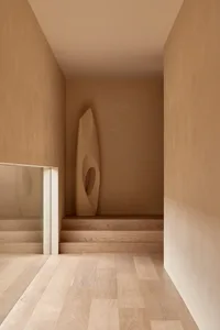 Empty hallway with a wooden floor and walls, featuring two sculptures on display in a calm and inviting atmosphere