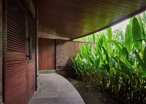 A doorway leading to a patio area surrounded by banana trees with growing fruit, set in a warm and inviting tropical environment