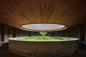 A well-designed interior space with a circular area surrounded by wooden walls, featuring potted plants and a central green plant