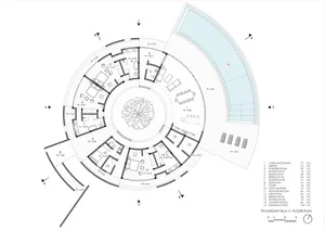 A modern building's interior floor plan features a circular design with various rooms and hallways, showcasing a mix of open areas and smaller rooms
