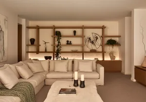 A well-lit living room with two couches, chairs, a dining table, and decorative elements such as potted plants, vases, and books, creating a cozy atmosphere