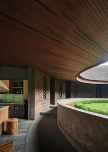 Open-plan kitchen and living area with wooden floors and walls, featuring appliances, a dining table, and comfortable seating