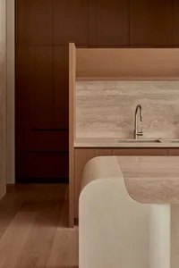 Sleek modern kitchen with wooden cabinets, marble countertops, and a large central island