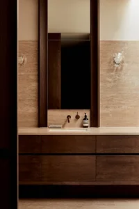 Bathroom with a wooden vanity, brown countertop, and two bottles, giving off a warm and inviting atmosphere