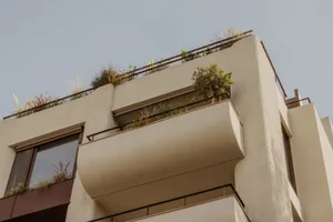 A building with multiple levels, balconies, and potted plants adding greenery throughout the scene