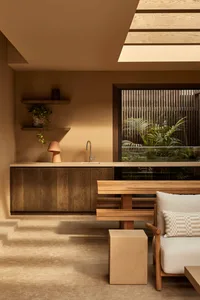 Warm and inviting kitchen and dining area with wooden floors and cabinets, surrounded by potted plants and decorative vases