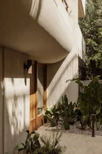 A white house with a patio area, potted plants, and natural light from windows
