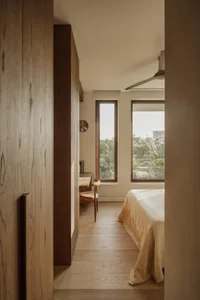 Bright and inviting bedroom with two beds, a desk area, and natural light from a large window