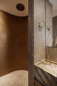 Bathroom with two sinks, a mirror, and brown tile walls creating a warm atmosphere