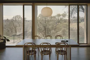 A warm and inviting dining area with a wooden table and chairs, surrounded by a symmetrical arrangement of additional chairs