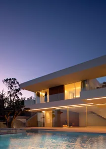 A modern house with glass walls, a balcony, and a cozy living room with a dining table and chairs
