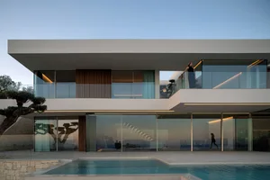 A large modern house with a pool in front, featuring multiple windows and a serene atmosphere
