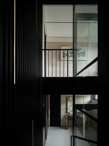 A dark and mysterious interior staircase with wooden steps and a black railing, featuring a painting on the wall above