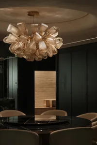 Dining area with two chairs and a glass table in a black and white color scheme, featuring a large hanging lamp