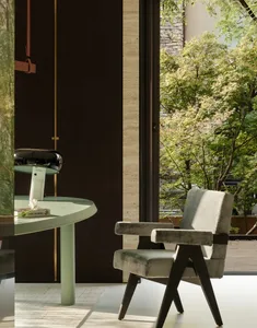 Cozy living space with a chair, dining table, and potted plant, featuring a warm and inviting atmosphere