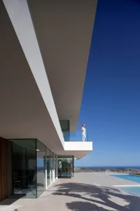 A modern house with a glass wall overlooking the ocean, featuring a serene and relaxing atmosphere with clean lines and minimalistic elements
