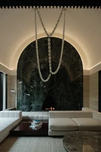 Warm and inviting living space with a stone wall, fireplace, two couches, a chair, and a dining table
