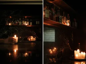 A sophisticated bar area with candles, wine glasses, and bottles in a dimly lit space