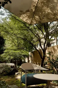 A cozy outdoor patio with a wooden bench, umbrella, and potted plants, creating a relaxing seating area