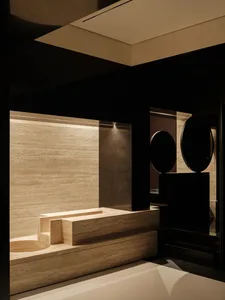A dark and moody bathroom with a black and white color scheme, featuring a sink and toilet, and two round objects, one near the sink and another near the toilet