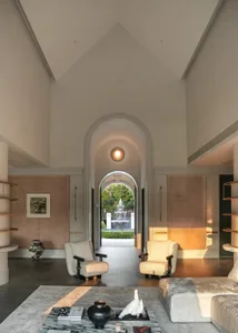Elegant living space with high ceiling, curved archway, multiple seating areas, and dining tables