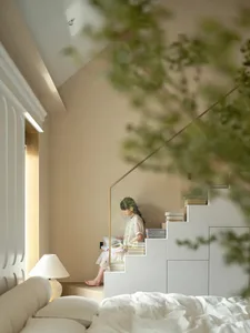 A woman reads a book on a staircase in front of a bookshelf, surrounded by a warm and cozy atmosphere with wooden stairs and several books on the shelf