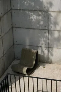 Empty concrete room with a cement chair in the center, creating a calm and minimalistic atmosphere