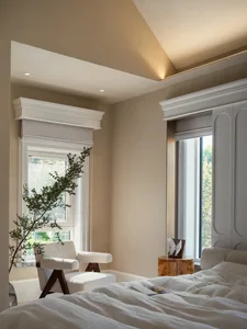 Cozy bedroom with a sitting area featuring two chairs, a potted plant, and a vase, creating a relaxing atmosphere