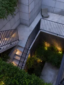 A dark and mysterious basement area with a metal staircase leading down, surrounded by shadows and a sense of depth
